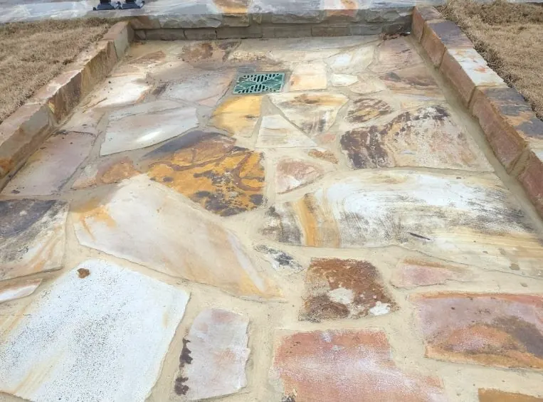 Multi-color flagstone patio with integrated drain grate and stone border