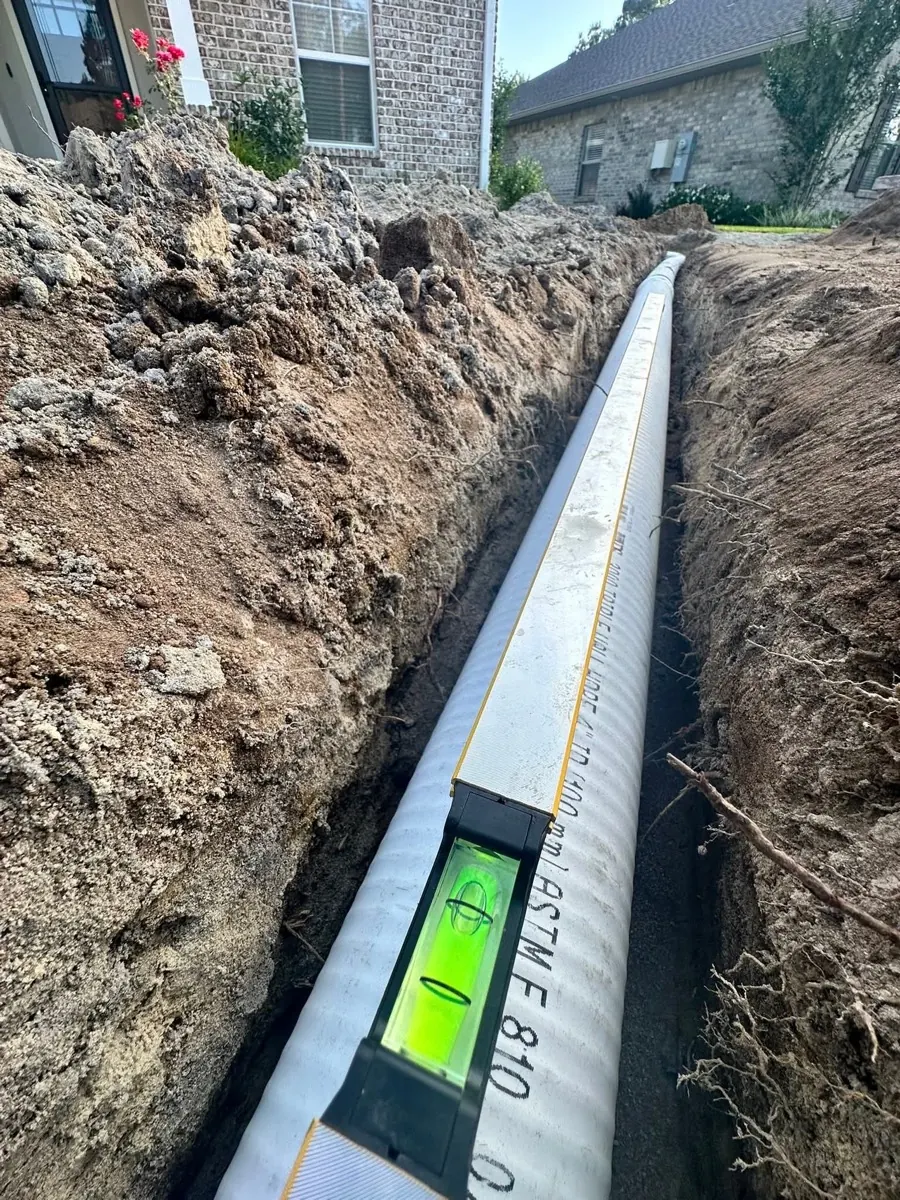 French drain pipe with level showing proper slope grade