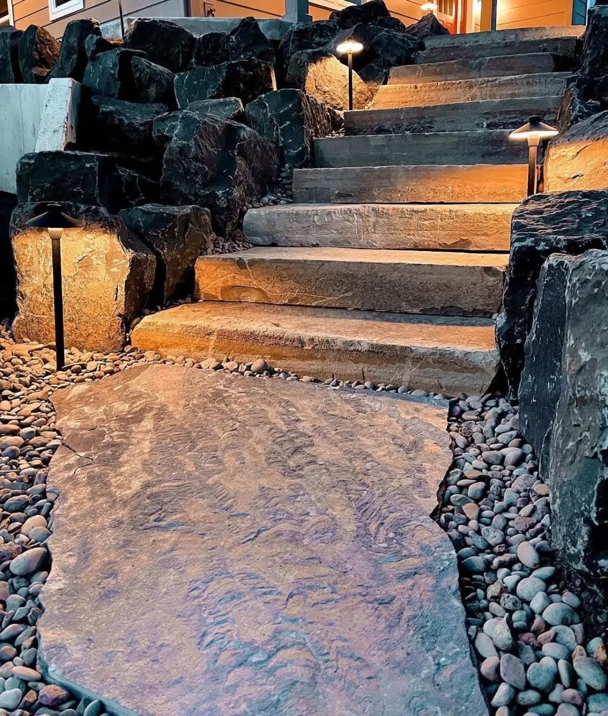 Natural stone steps dramatically lit with pathway lights and boulder accents at night