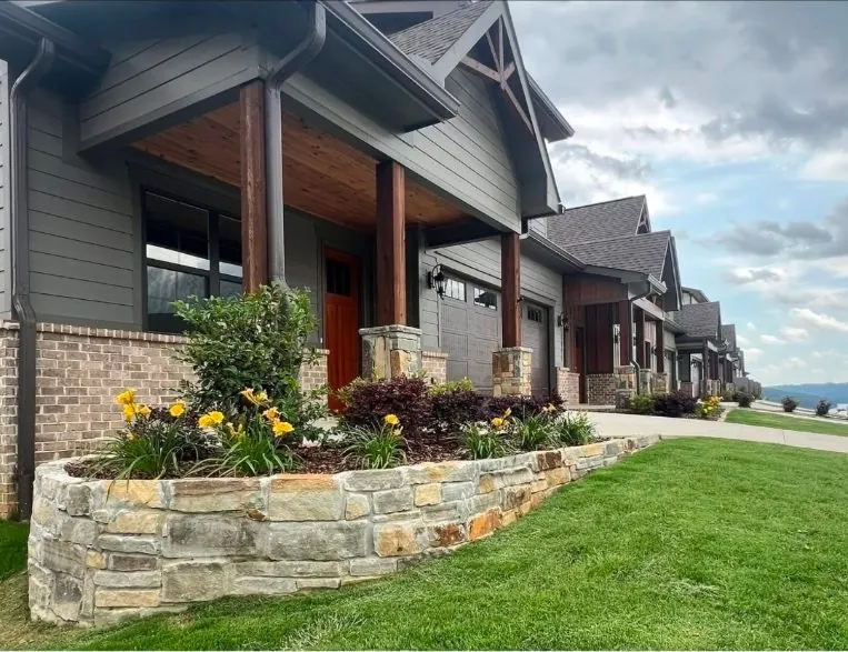 Stone retaining wall flower bed with yellow flowers at craftsman-style home